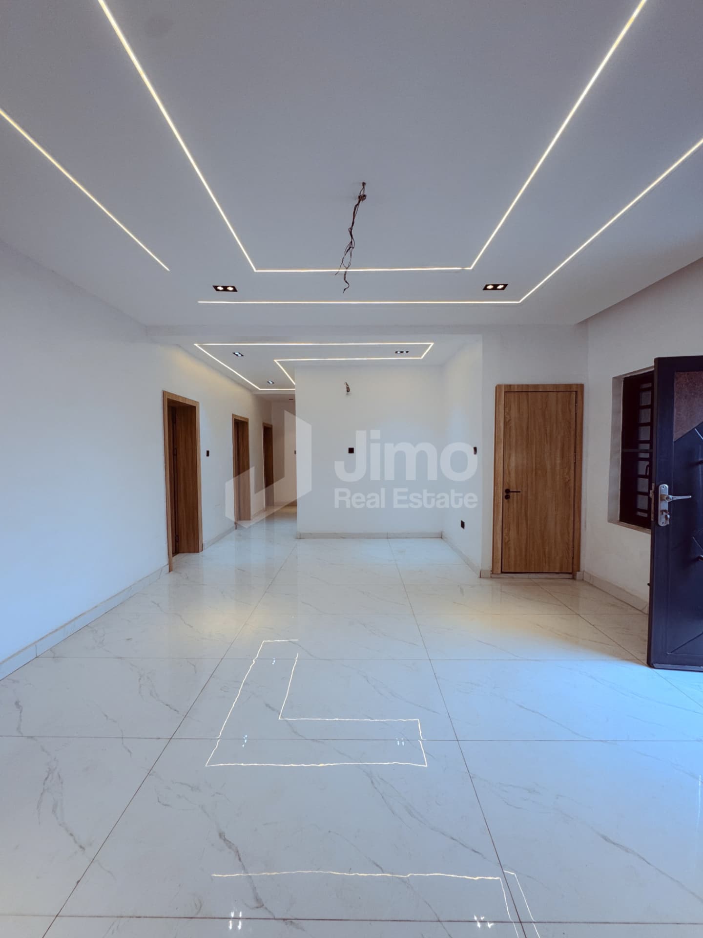 Spacious living area with marble-look tiles and cove lighting